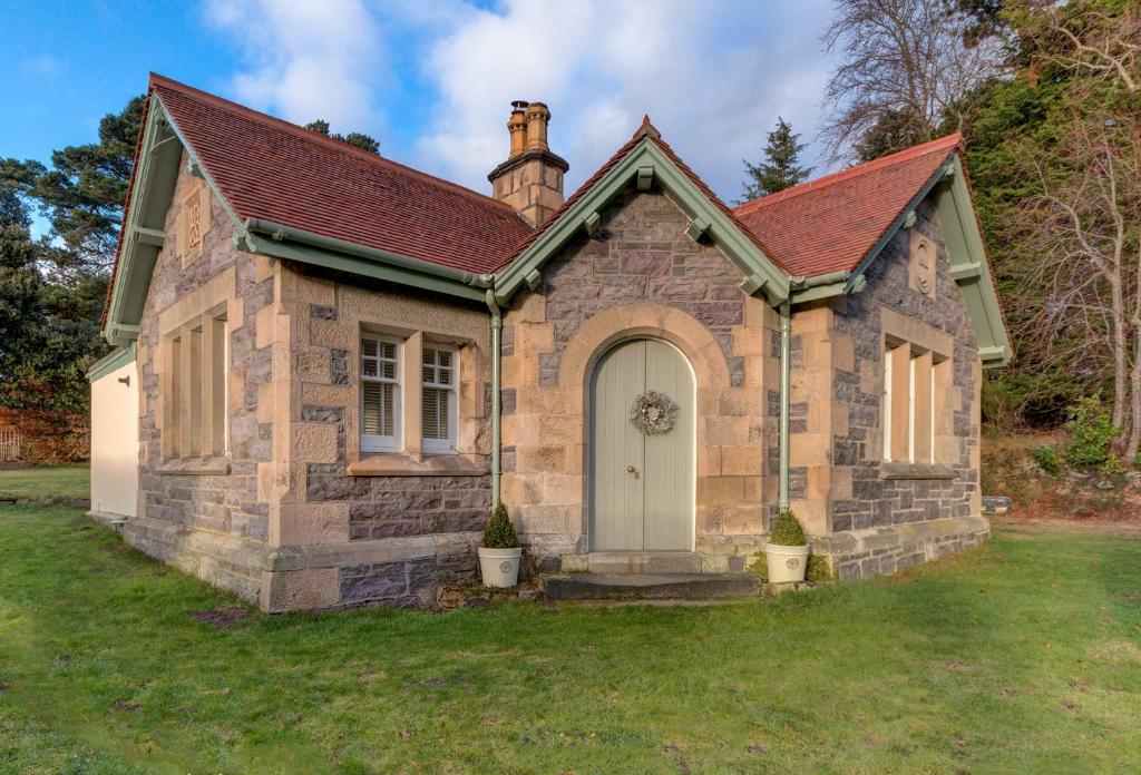 uma pequena casa de tijolos com uma porta branca em Firlands Lodge em Forres