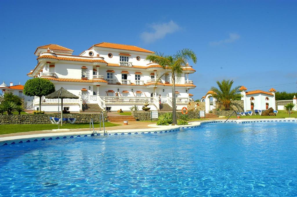 a large house with a swimming pool in front of it at Hotel Diufain in Conil de la Frontera