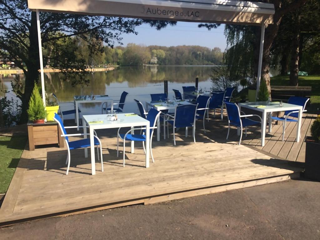 un gruppo di tavoli e sedie su una terrazza accanto a un lago di L'Auberge du Lac a Annay
