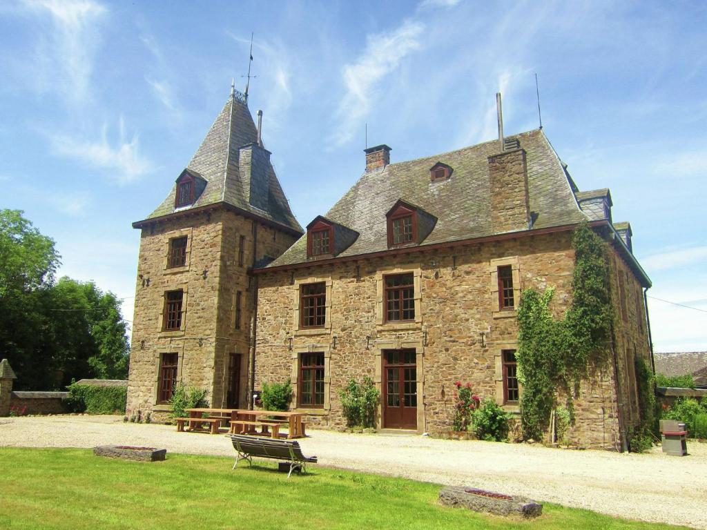 a large stone building with two towers and a bench at Luxurious Castle with Private Pool and Sauna in Basse-Bodeux