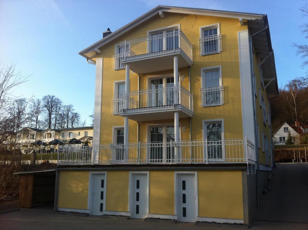 - un bâtiment jaune avec des fenêtres et des balcons blancs dans l'établissement Villa Rügen, à Sellin