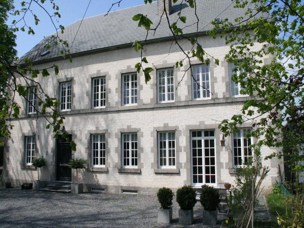 um grande edifício de tijolos brancos com janelas brancas em Charming holiday home in Ardennes and large garden em Honnay