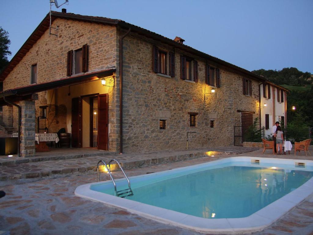 a house with a swimming pool in front of a building at Tasteful holiday home in Modigliana with garden in Modigliana