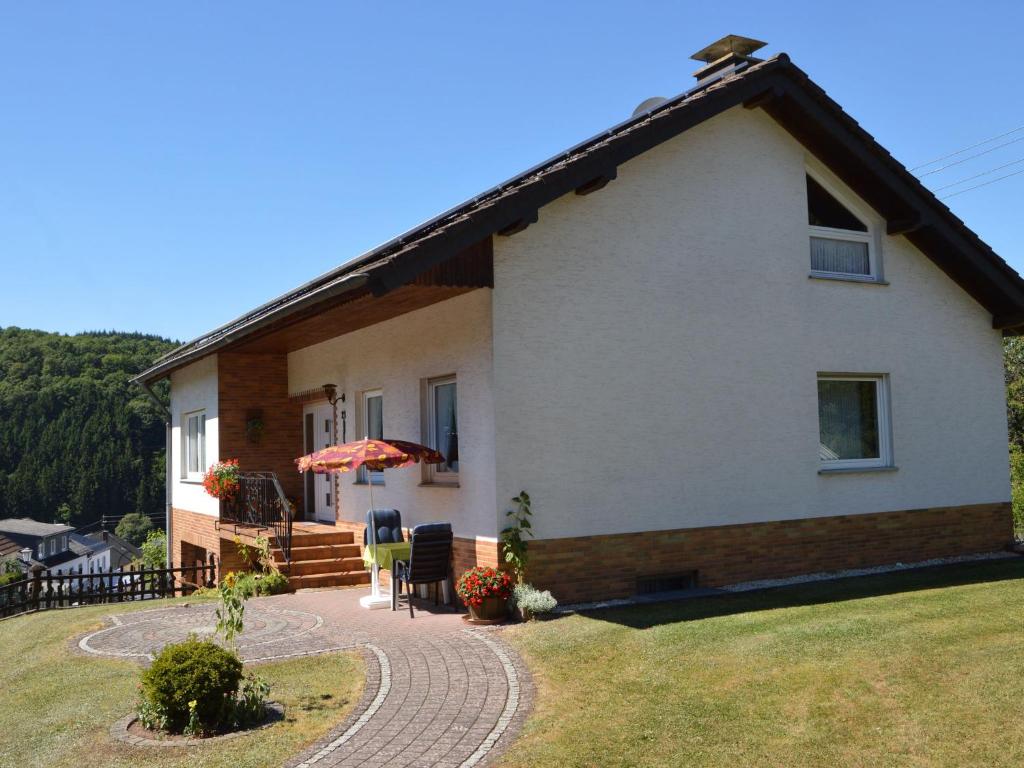 a white house with a patio and a lawn at Holiday home in Densborn with garden in Zendscheid