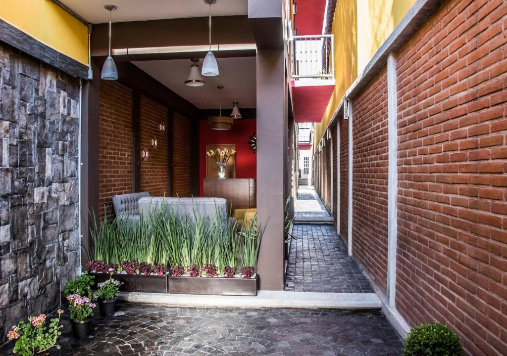 an alleyway with a brick wall and plants on it at Hotel Casa Aurora in Querétaro