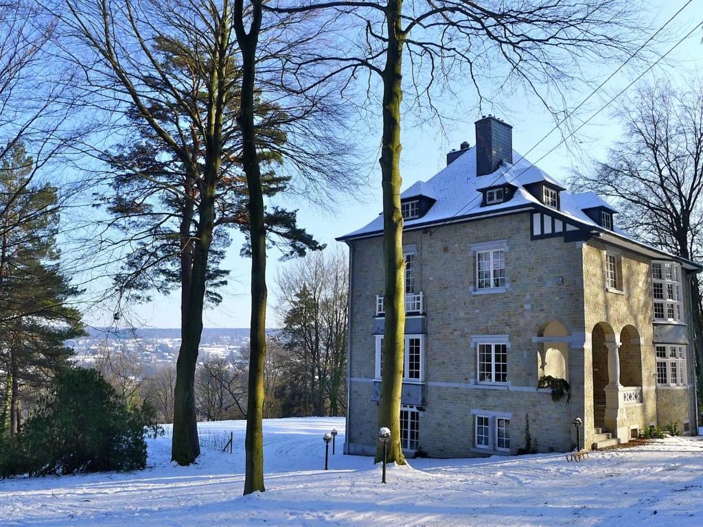 una gran casa de piedra en la nieve con árboles en Villa in Spa with Sauna Recreation and Playroom, en Spa