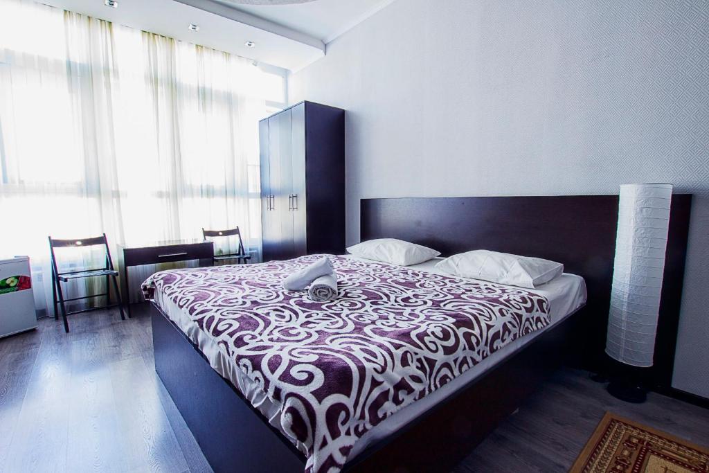 a bedroom with a large bed with a black and white blanket at Mini Hotel Bereket Dip in Astana