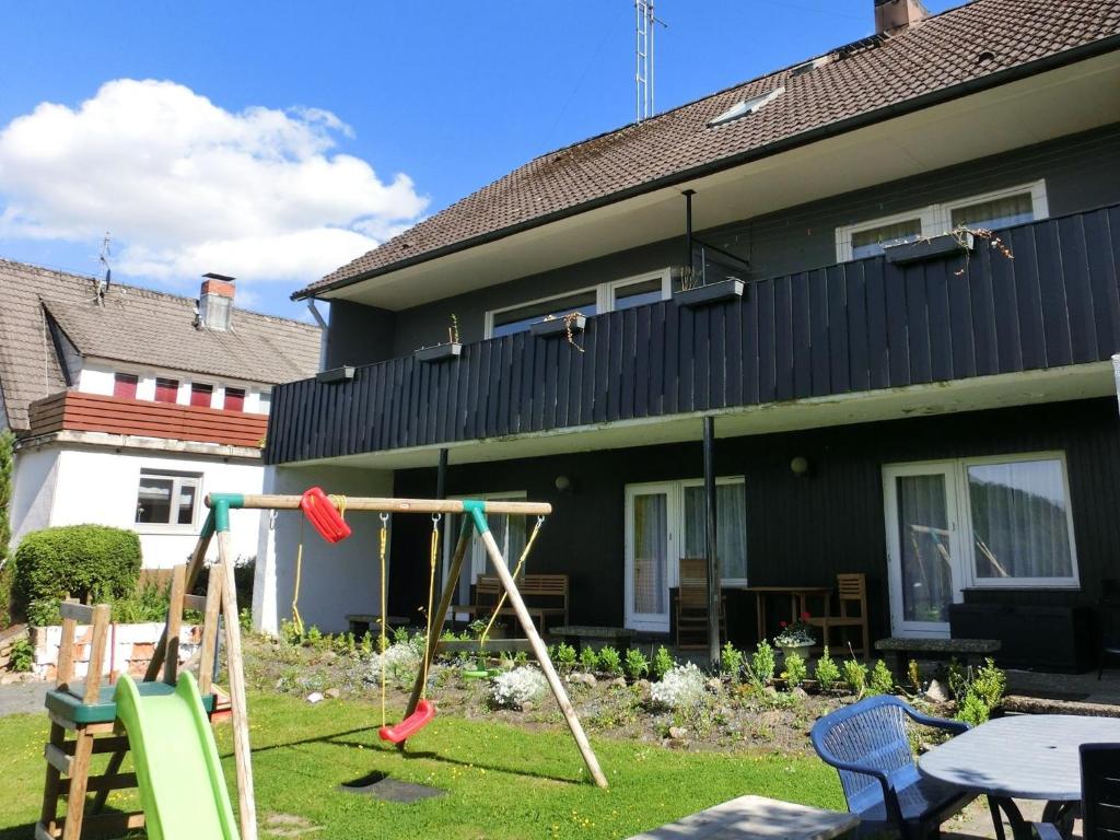 ヴィルデマンにあるMesmerizing Apartment in Wildemann Germany with Gardenの家の前に2本のブランコがある庭