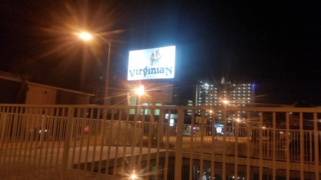 een verlicht bord boven op een gebouw 's nachts bij The Virginian Motel in Myrtle Beach