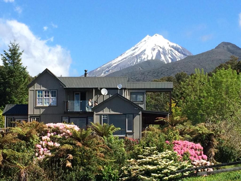 a house with a snow covered mountain in the background at Georges BnB Nature and Lifestyle Retreat in New Plymouth