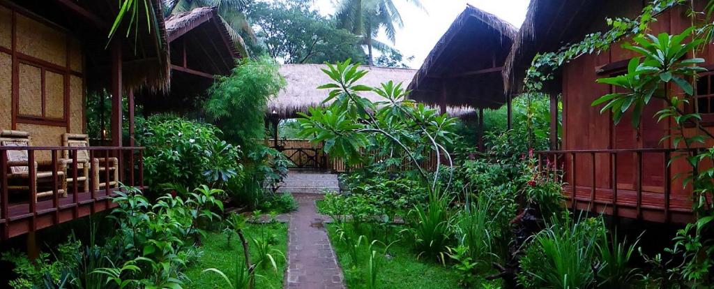 um jardim com um caminho que leva a uma casa em Shibui Garden Bungalows and Restaurant em Tanjung