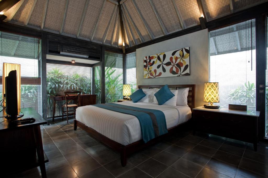 a bedroom with a bed in a room with windows at Komea Villa in Canggu