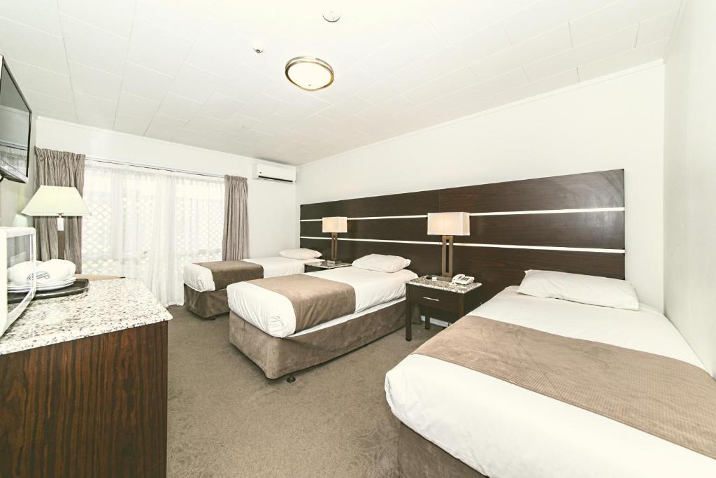 a hotel room with two beds and a television at Airport Gateway Hotel in Auckland
