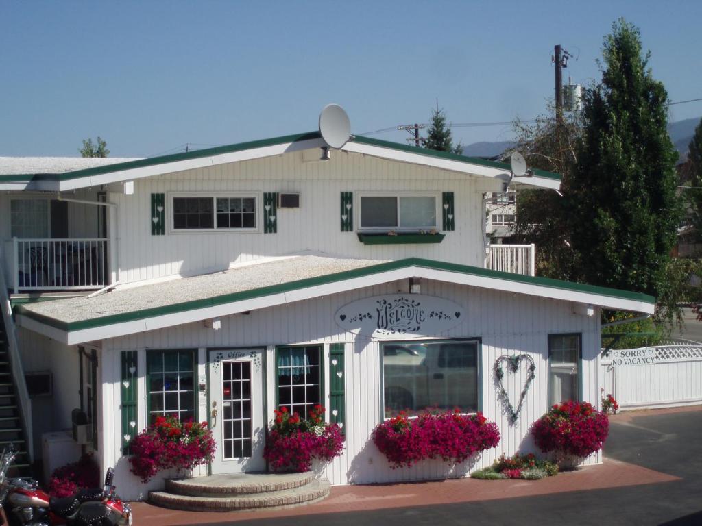 a white building with flowers in front of it at Empire Motel in Penticton