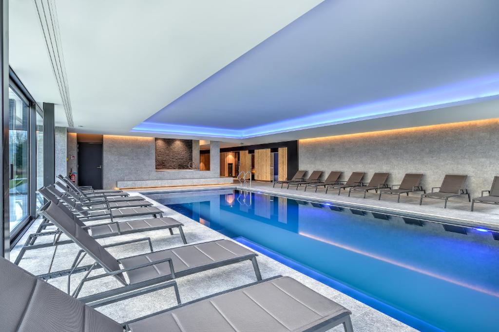une piscine avec des chaises longues et un hôtel dans l'établissement R hotel experiences, à Sougné-Remouchamps