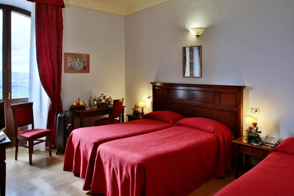 Hotel Windsor Savoia في أسيسي: غرفة نوم بسرير احمر مع بطانية حمراء