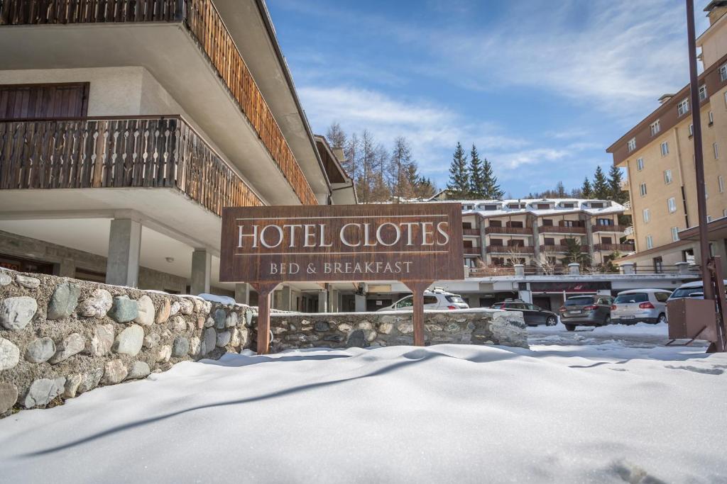 a hotel cloths sign in the snow in front of a building at Hotel Clotes in Sauze dʼOulx