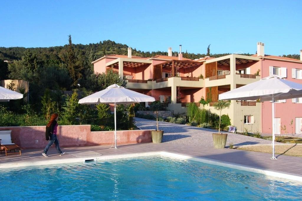 une personne se promenant près d'une piscine avec parasols dans l'établissement Astrolabe Hotel, à Khrónia