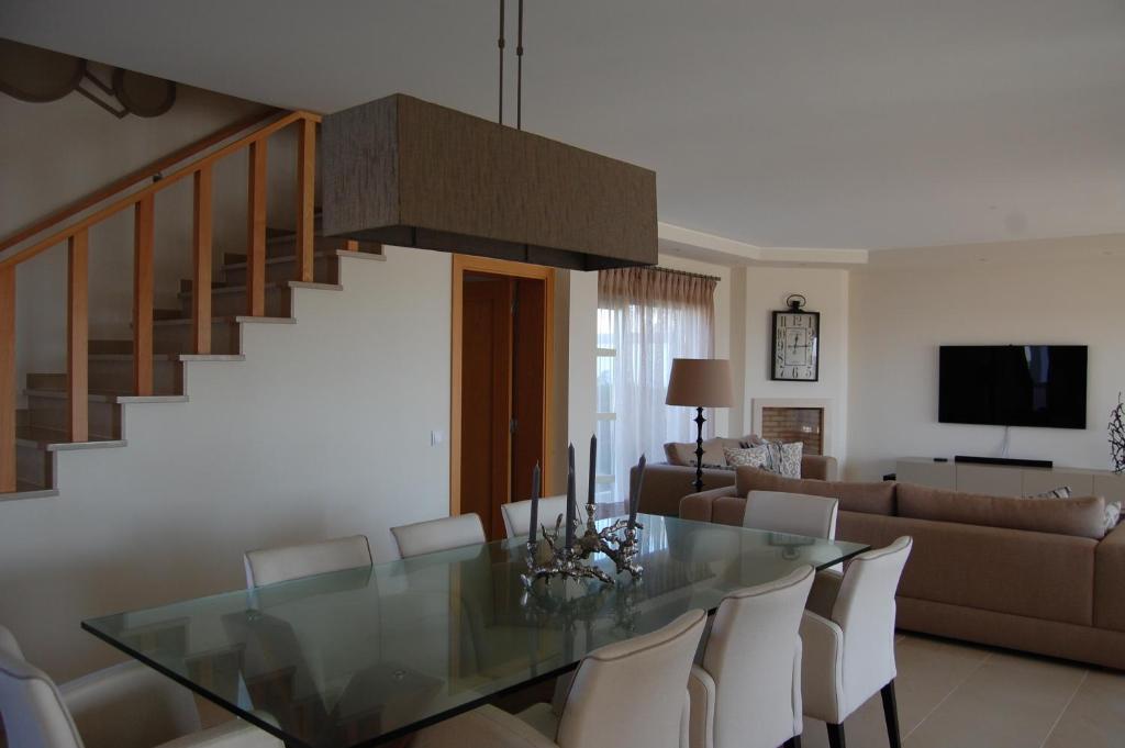 uma sala de jantar com uma mesa de vidro e cadeiras brancas em Villa Golf 6 em Óbidos