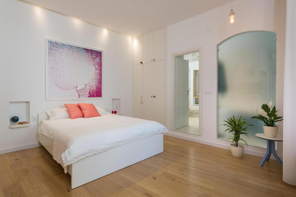 a white bedroom with a bed and a large mirror at That place studio apartment in Trogir