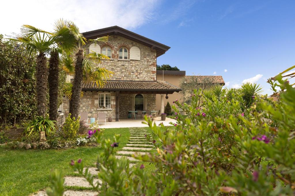 a stone house with palm trees and a yard at Villa dei Colori in Toscolano Maderno