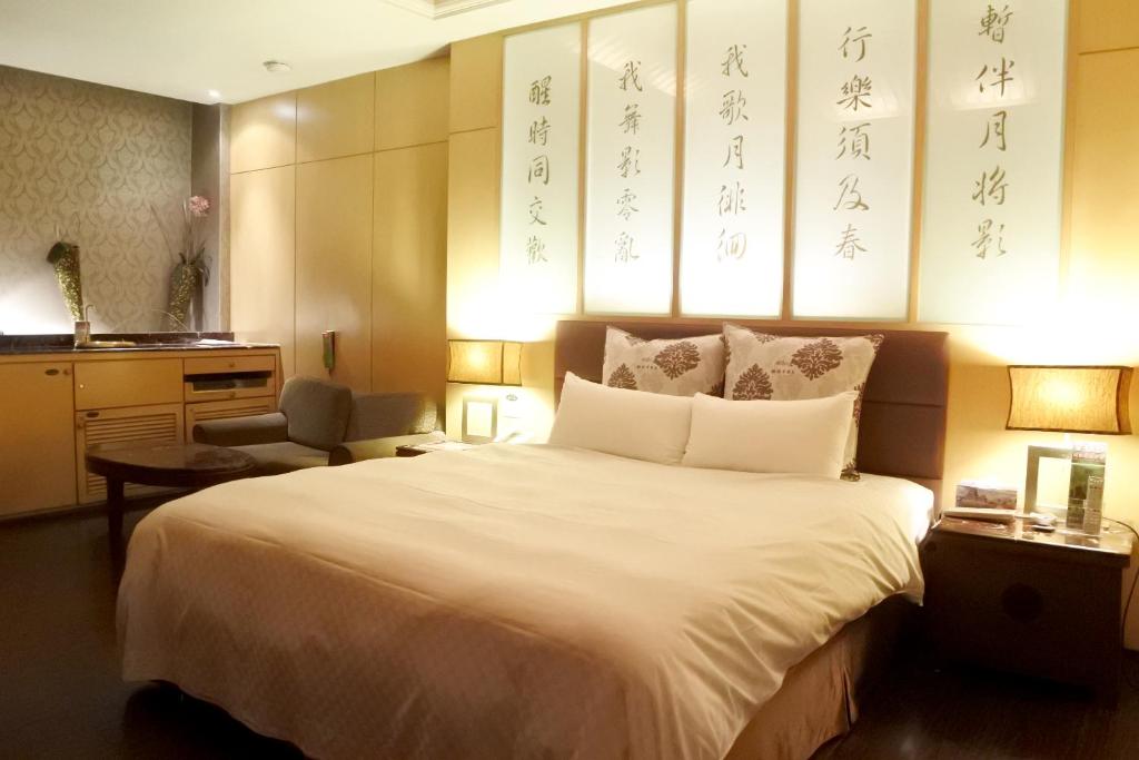 a bedroom with a large white bed and a chair at North Country Motel in Yingge