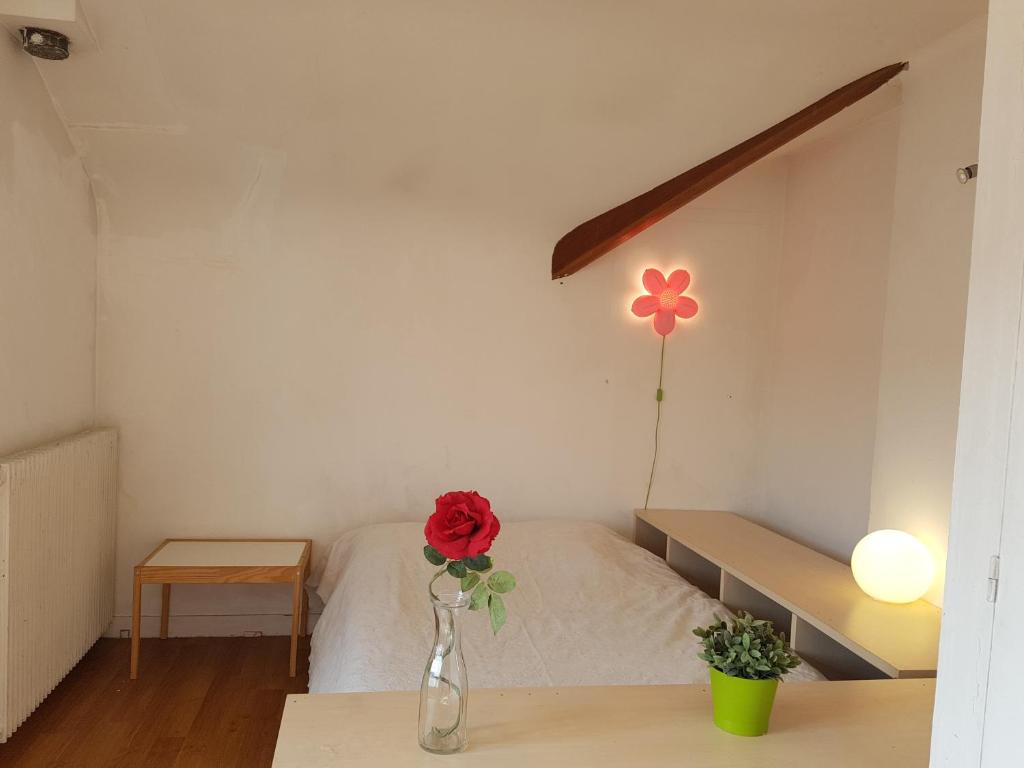 una camera da letto con un vaso con un fiore di NDP Family (Ndong Du Pierrier) a Montigny-lès-Cormeilles