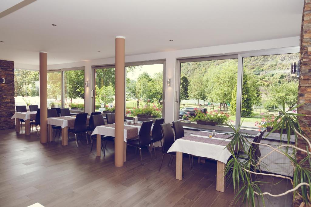 ein Restaurant mit Tischen und Stühlen und großen Fenstern in der Unterkunft Hotel Garni Reis in Treis-Karden
