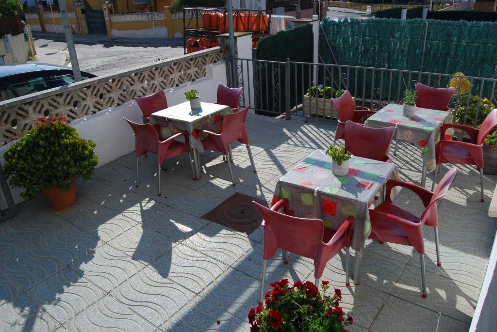 a patio with red chairs and tables and a fence at Hotel Paradís in Torredembarra