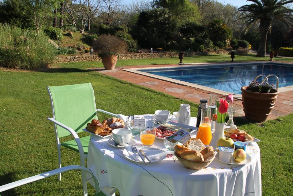 un tavolo con cibo e bevande accanto alla piscina di Mas Vilosa Bed and Breakfast a Corçà