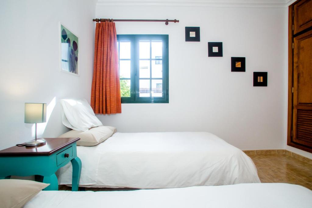 1 dormitorio con 2 camas y ventana en Sunny Golf Villas, en Puerto del Carmen