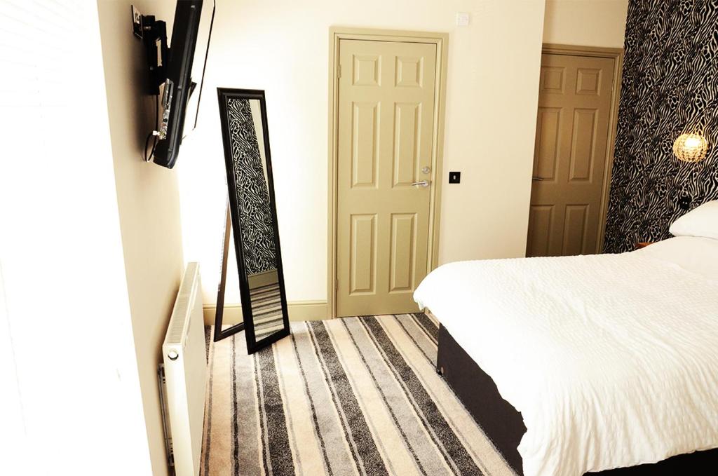 a bedroom with a bed and a mirror next to a door at Frankies Wine Bar & Lodge in Disley