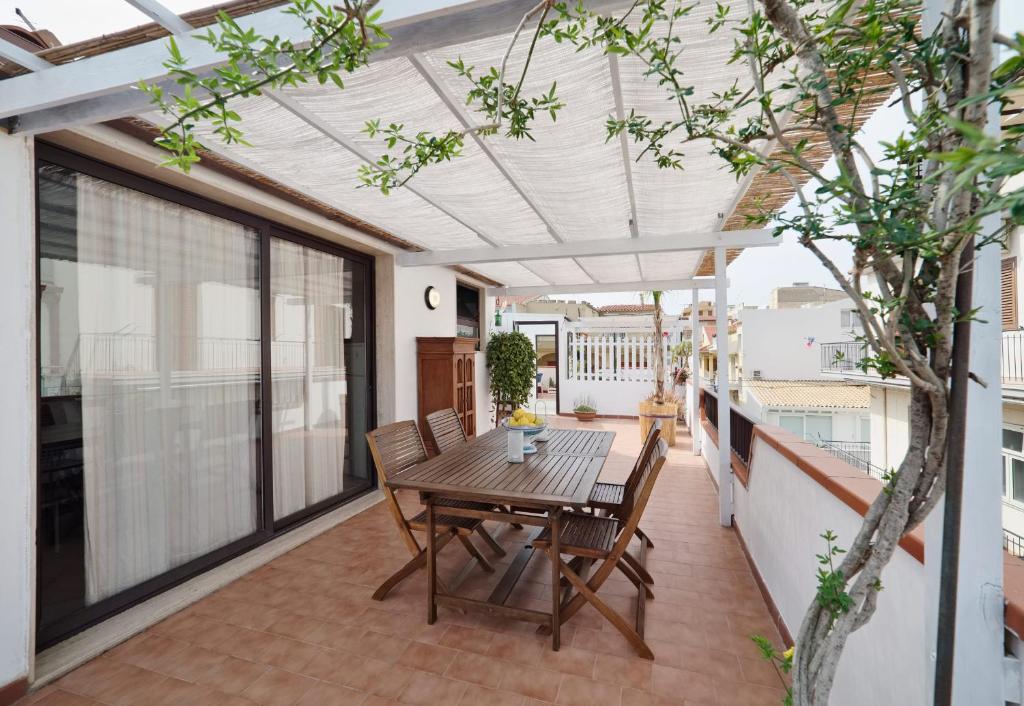 a patio with a wooden table and chairs on a balcony at Le Terrazze di Angela in Marina di Ragusa