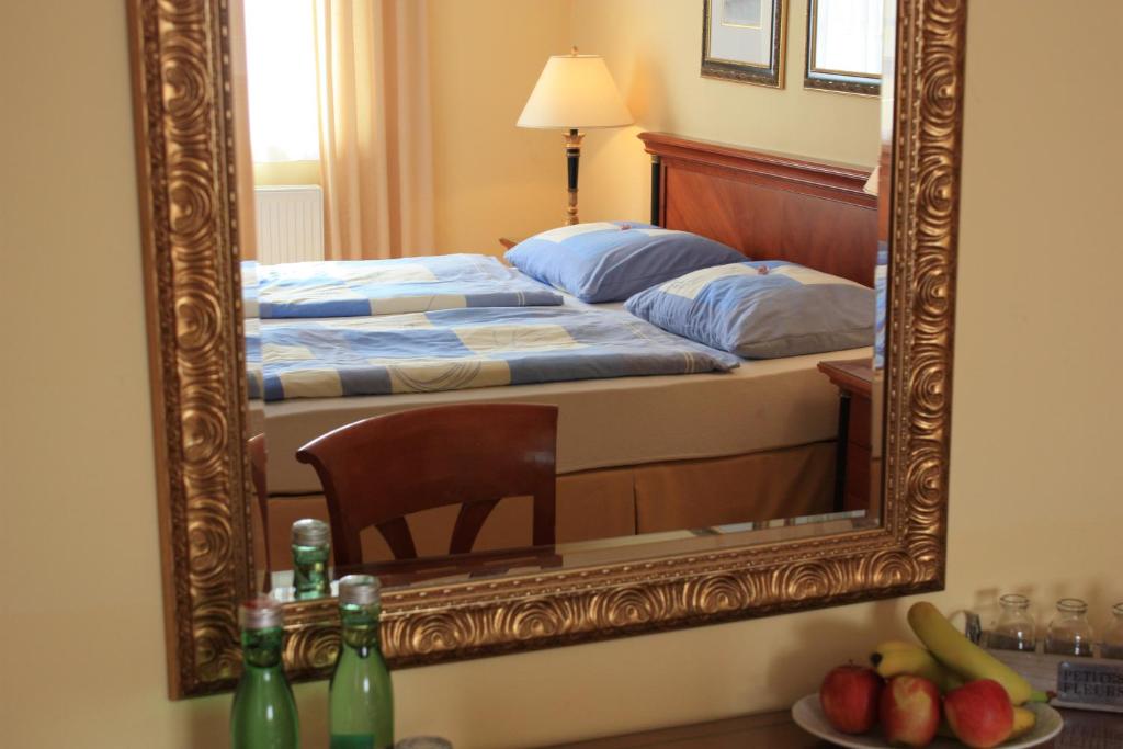 lustro odzwierciedlające sypialnię z łóżkiem i krzesłem w obiekcie Hotel Zachs w mieście Sankt Margarethen im Burgenland