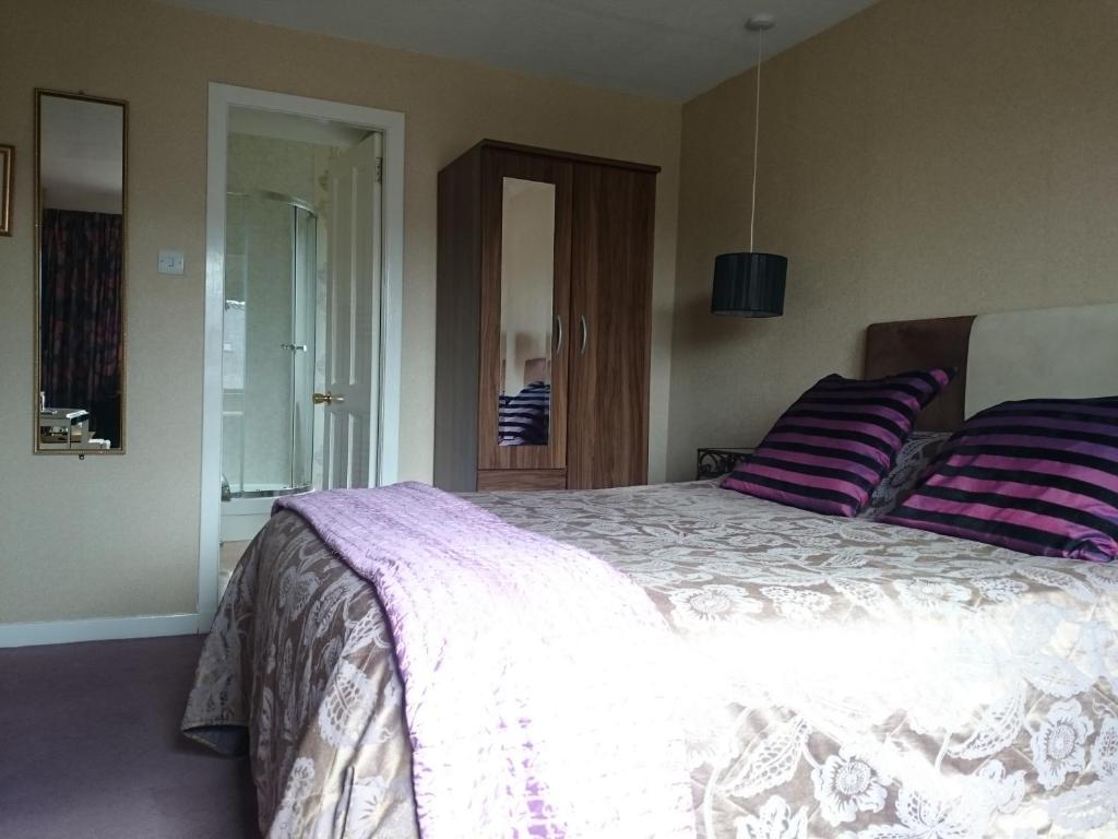 a bedroom with a large bed with purple and purple pillows at Albert Hotel in Peterhead