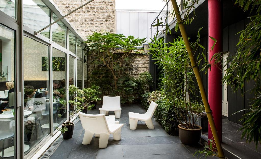 パリにあるル カルティエ ベルシー-スクエアの白い椅子と植物のある中庭