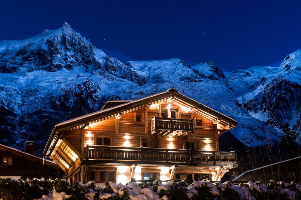 a log cabin with snow covered mountains in the background at Chalet Cree - Haute Collection in Chamonix