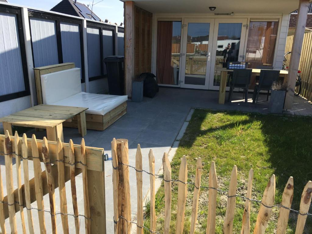 een achtertuin met een houten hek en een bank bij Huisje 19 Zoutelande in Zoutelande