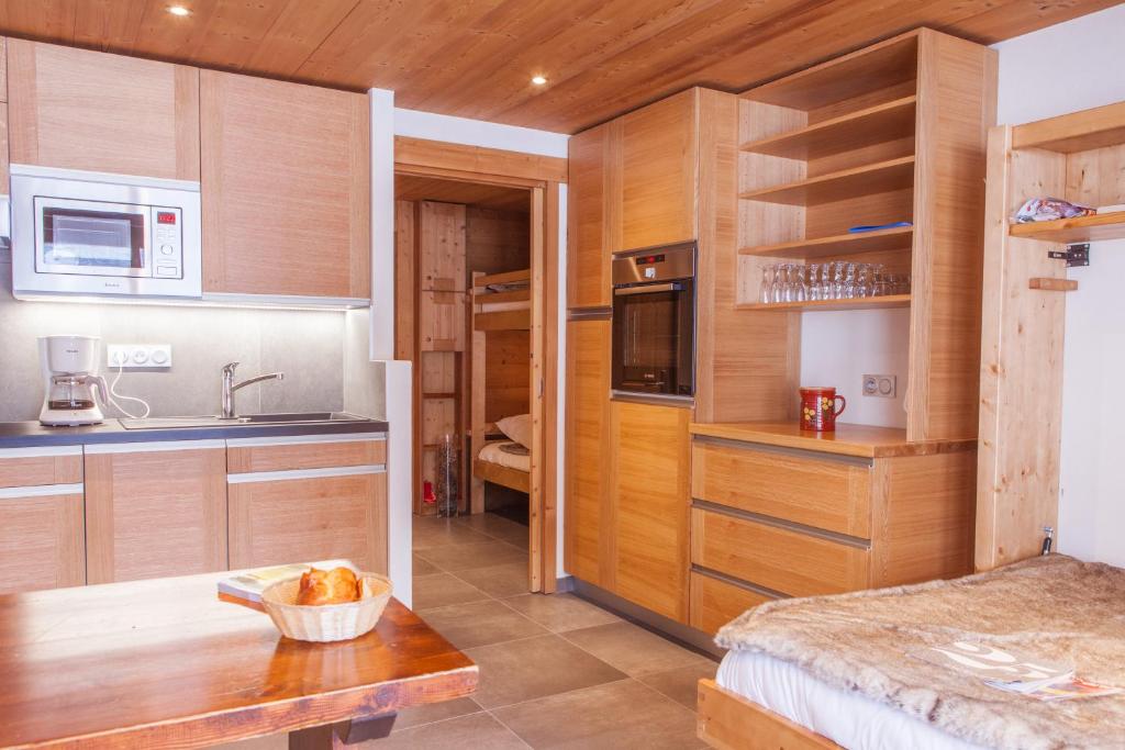 a kitchen with wooden cabinets and a table in a room at Studio Beauregard in Le Grand-Bornand