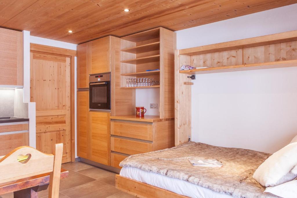 a small bedroom with a bed and a kitchen at Studio Beauregard in Le Grand-Bornand