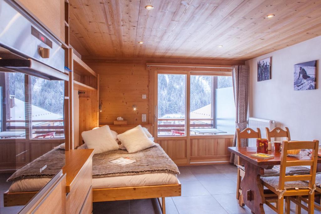 um quarto com uma cama, uma secretária e uma janela em Studio Beauregard em Le Grand-Bornand