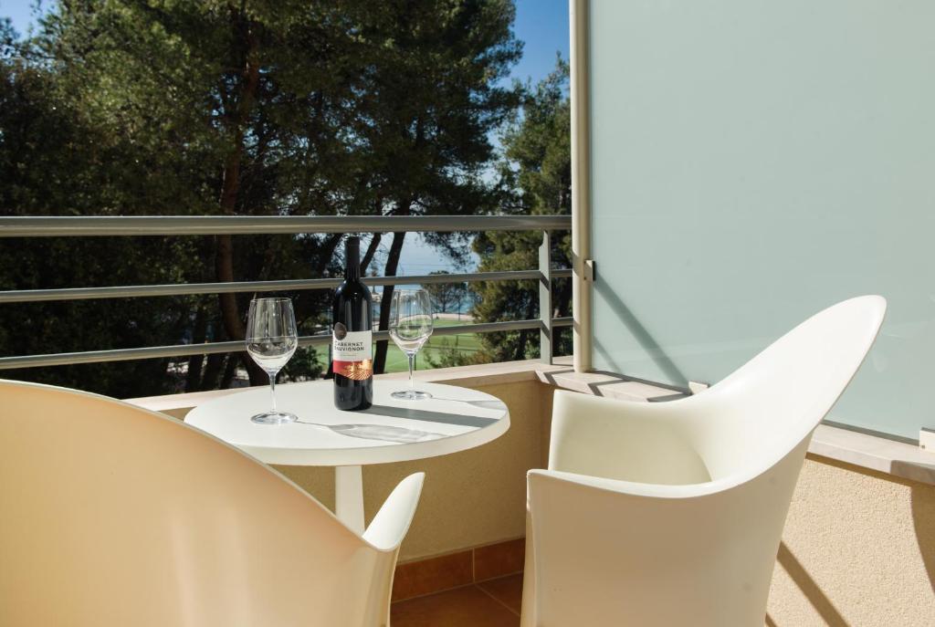 a balcony with white chairs and a table with wine glasses at Sunset Apartments in Podstrana
