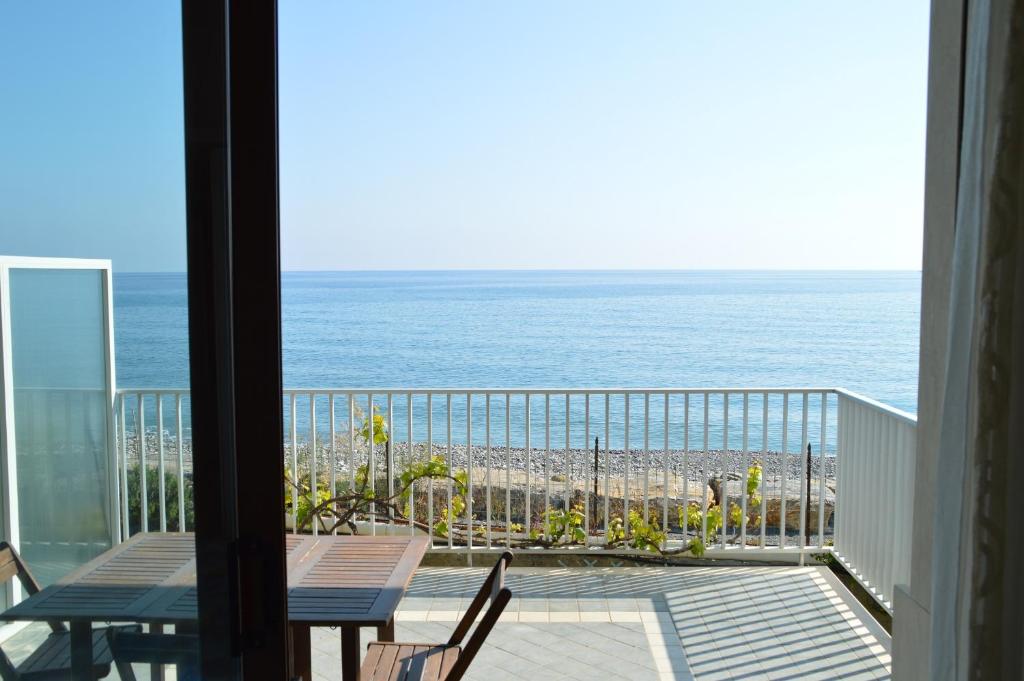 Riva Beach Apartment في ريفا ليجوري: شرفة مع طاولة وكراسي والمحيط