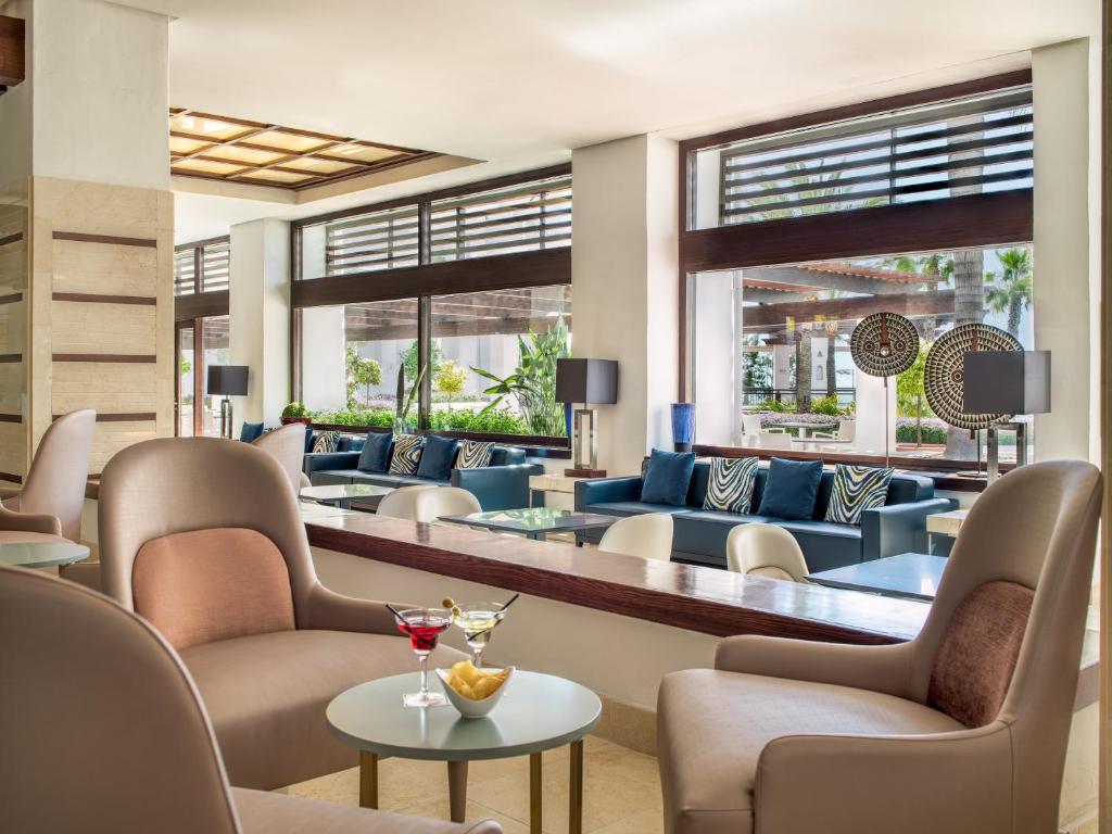 a hotel lobby with chairs and tables and windows at H10 Estepona Palace in Estepona