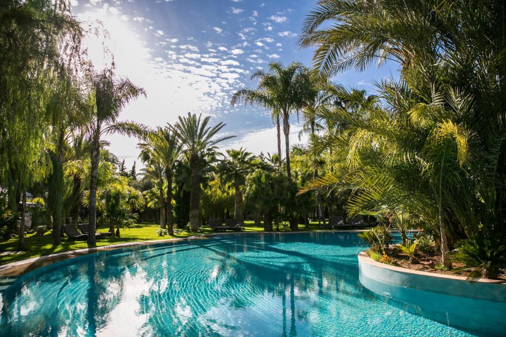 una piscina con palmeras en un complejo en Lodge K en Marrakech