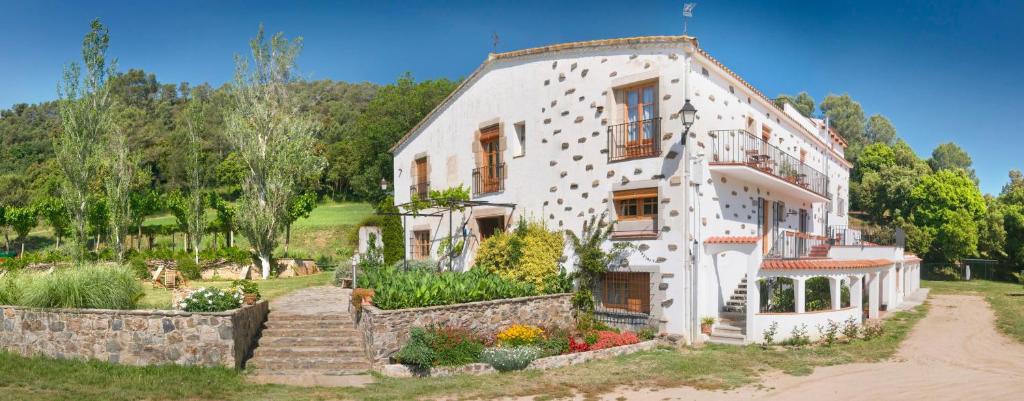 a large white house with a garden in front of it at Can Rosich in Santa Susanna