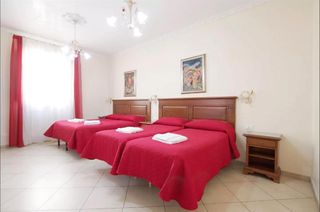 ローマにあるAnthony House, Via Villafranca 2, Castro Pretorioのベッドルーム1室(赤いシーツが敷かれたベッド3台、窓付)