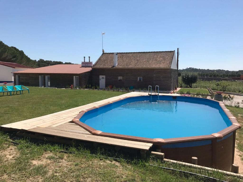 a large swimming pool with a wooden deck and a house at Monte da Barragem in Montargil