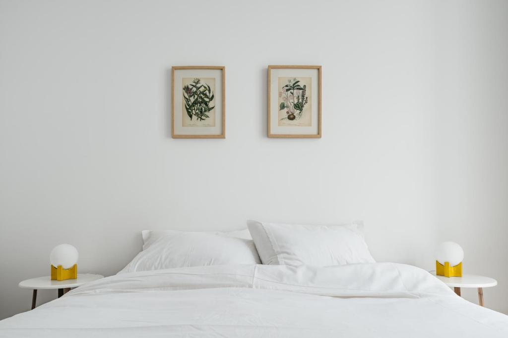 uma cama branca com duas fotografias na parede em The Lisboans Apartments em Lisboa