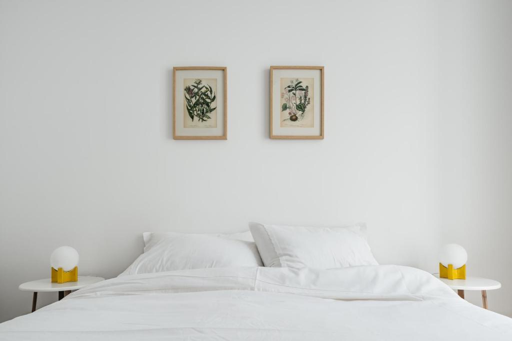 a white bed with two pictures on the wall at The Lisboans Apartments in Lisbon